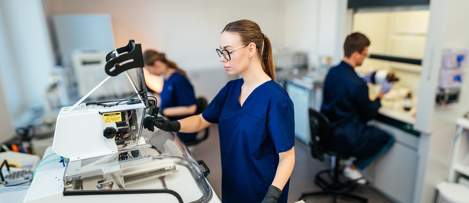 Three medical professionals in a lab, two sat down and one stood in front of a medical device. 